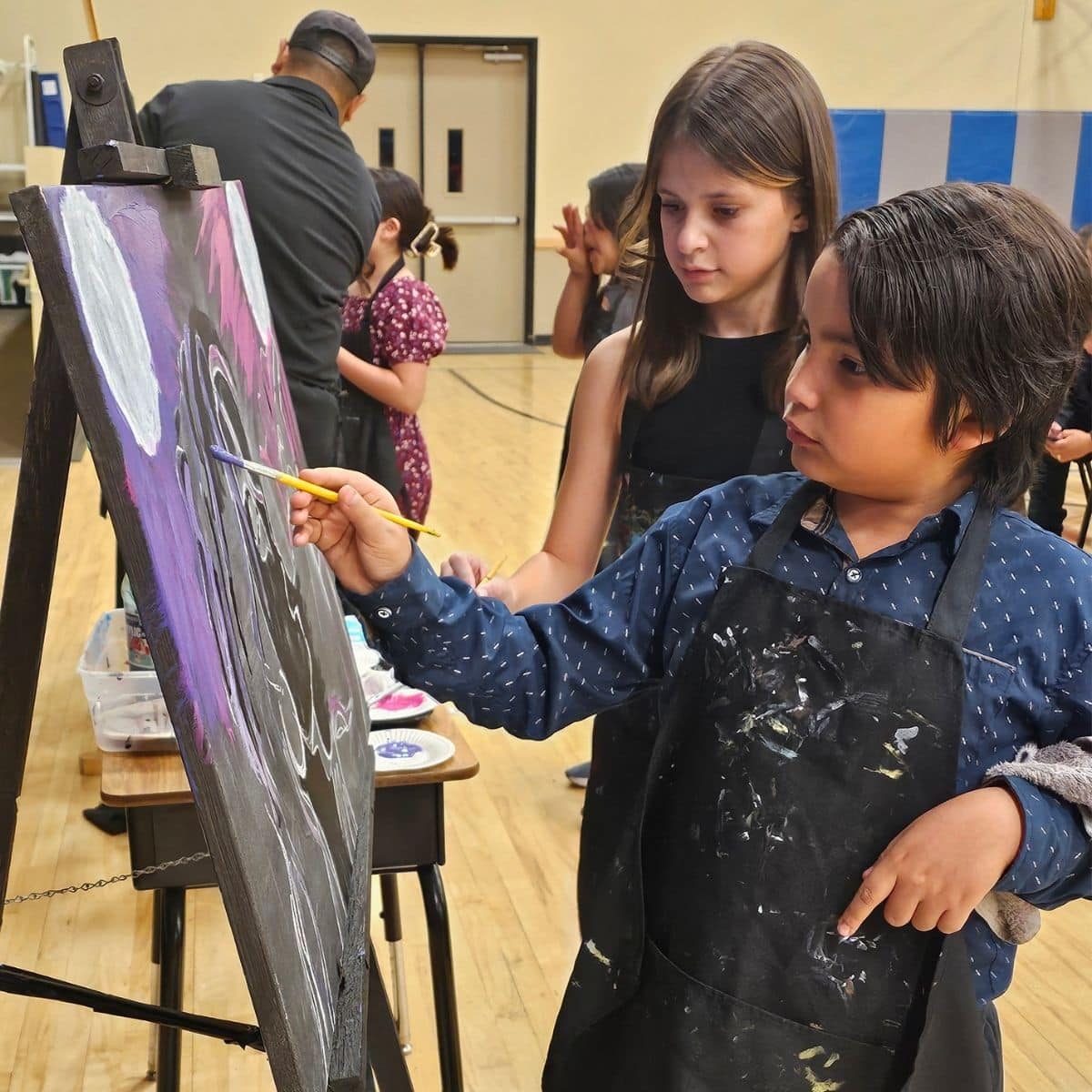 A teacher working one-on-one with a student on a painting